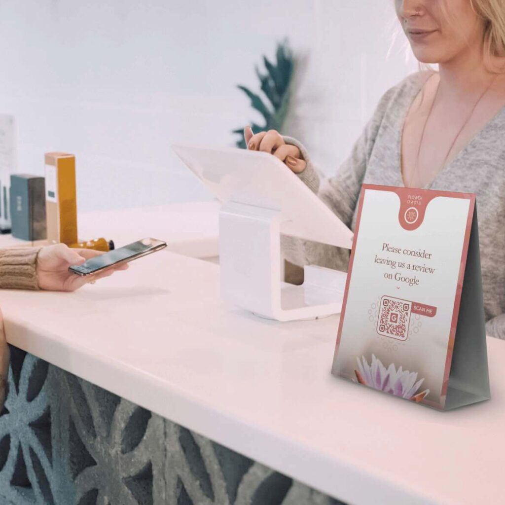 A table tent with a QR Code on it on a counter between a customer and a retail clerk.